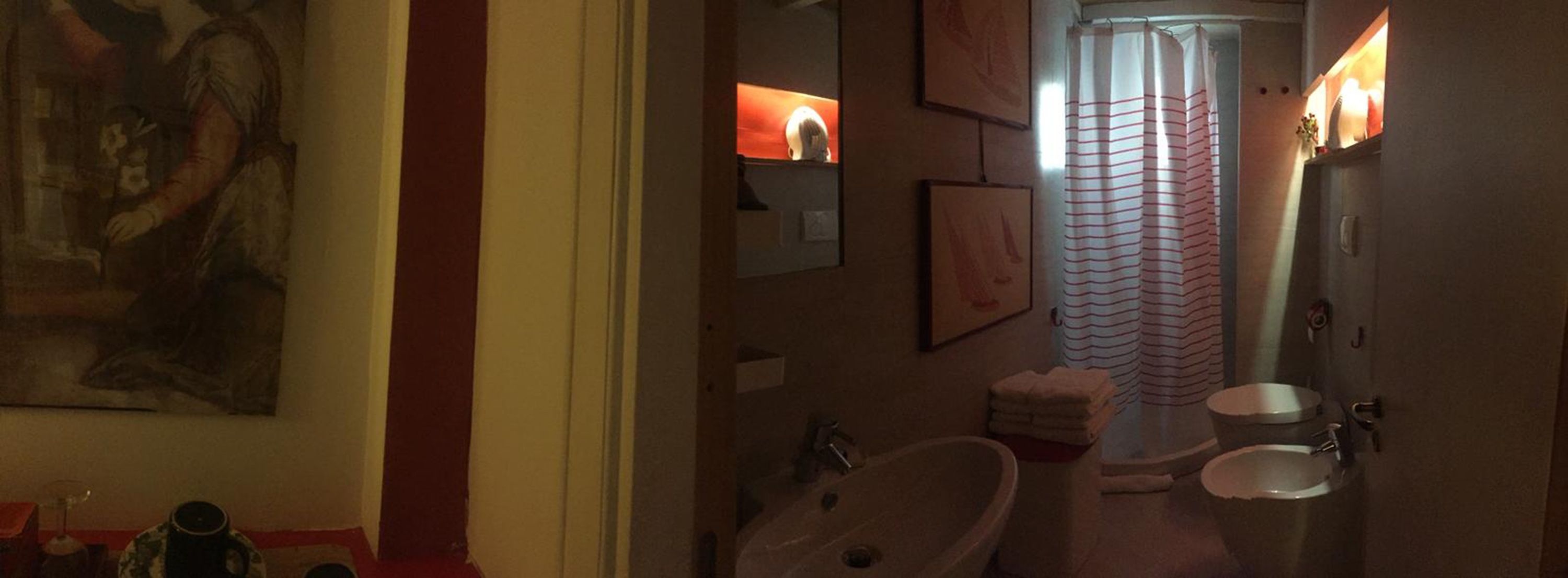 A bathroom with a large mirror, two sinks, a shower curtain, and a framed picture on the wall.