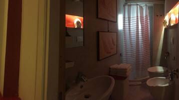 A bathroom with a large mirror, two sinks, a shower curtain, and a framed picture on the wall.