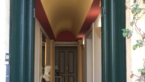 A narrow hallway with a red ceiling, green doors, and a patterned carpet.