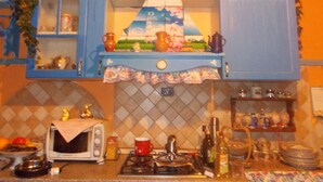 A kitchen with blue cabinets, a microwave, a stove, and various kitchen items. - L'Antica Locanda (Iglesias)