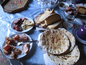 A table with various food items including bread, cheese, and cured meats. - L'Antica Locanda (Iglesias)