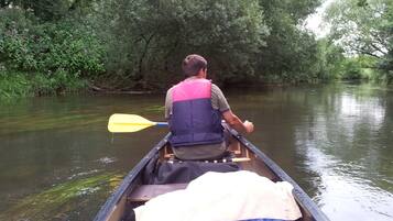A person in a canoe on a river surrounded by dense greenery.