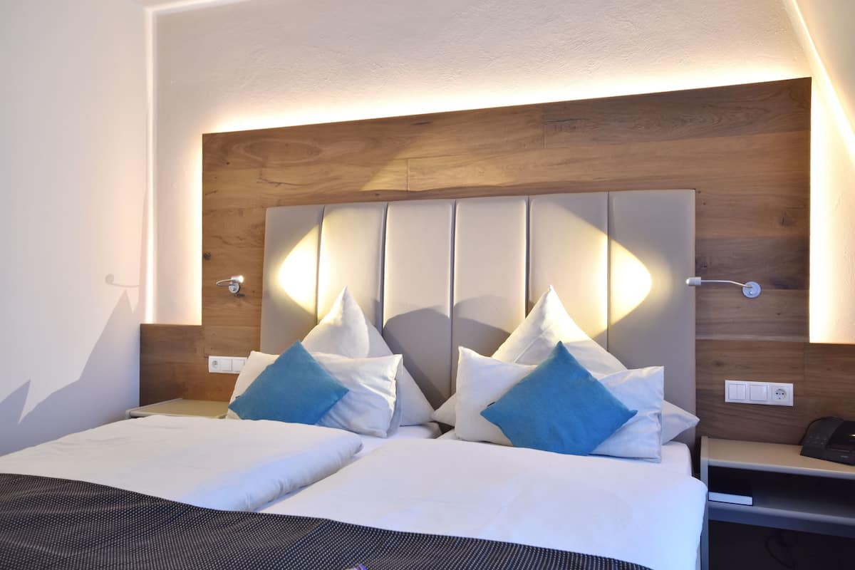A double bed with a wooden headboard, two bedside tables, and a nightstand with a phone.