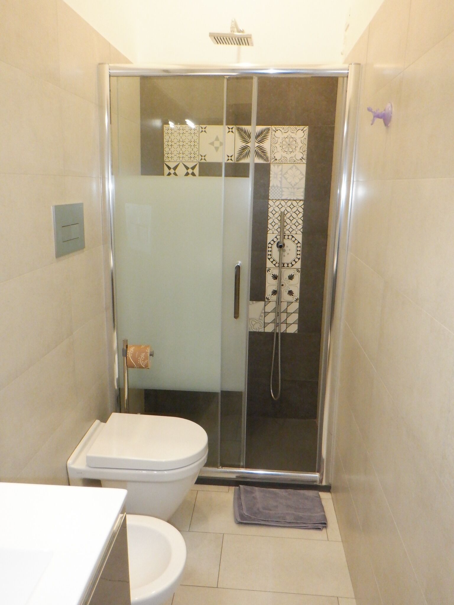 A bathroom with a glass-enclosed shower, a toilet, and a sink.