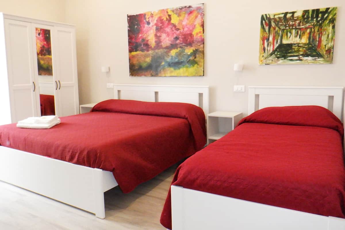 A hotel room with two beds, white headboards, and colorful abstract paintings on the walls.