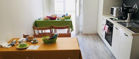 A compact kitchen with a dining area, featuring a table set for two, a microwave, and a small oven.