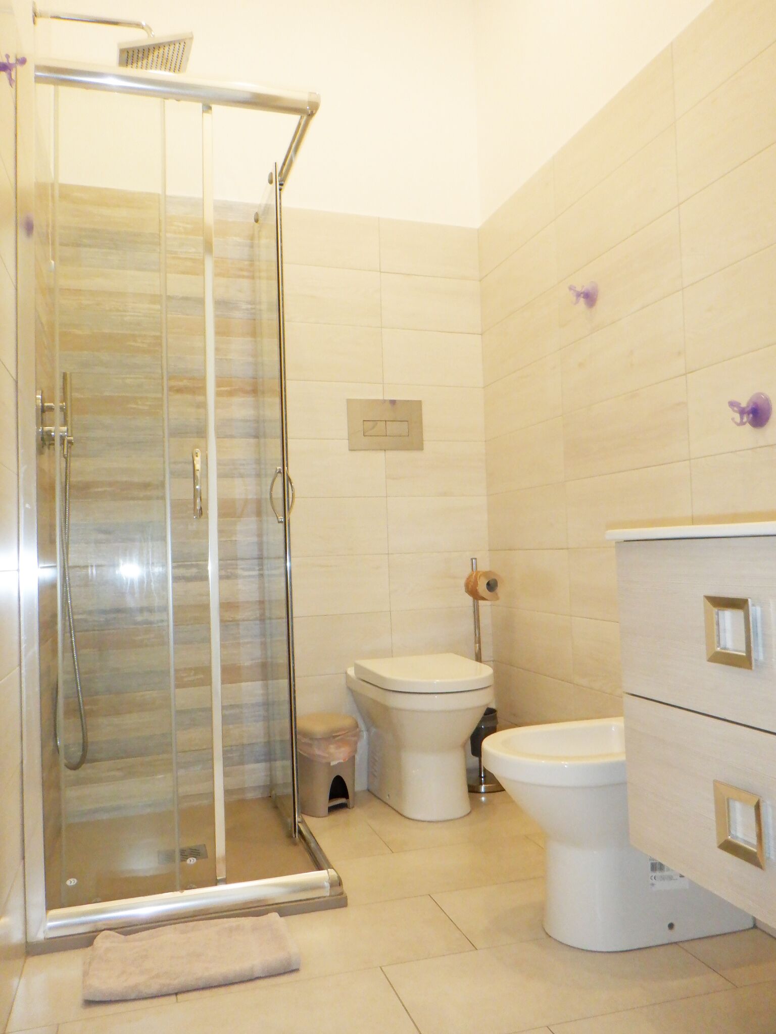 A bathroom with a glass-enclosed shower, a toilet, and a vanity with drawers.