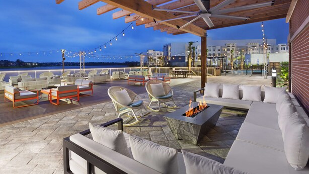 An outdoor patio with seating, a fire pit, and string lights.