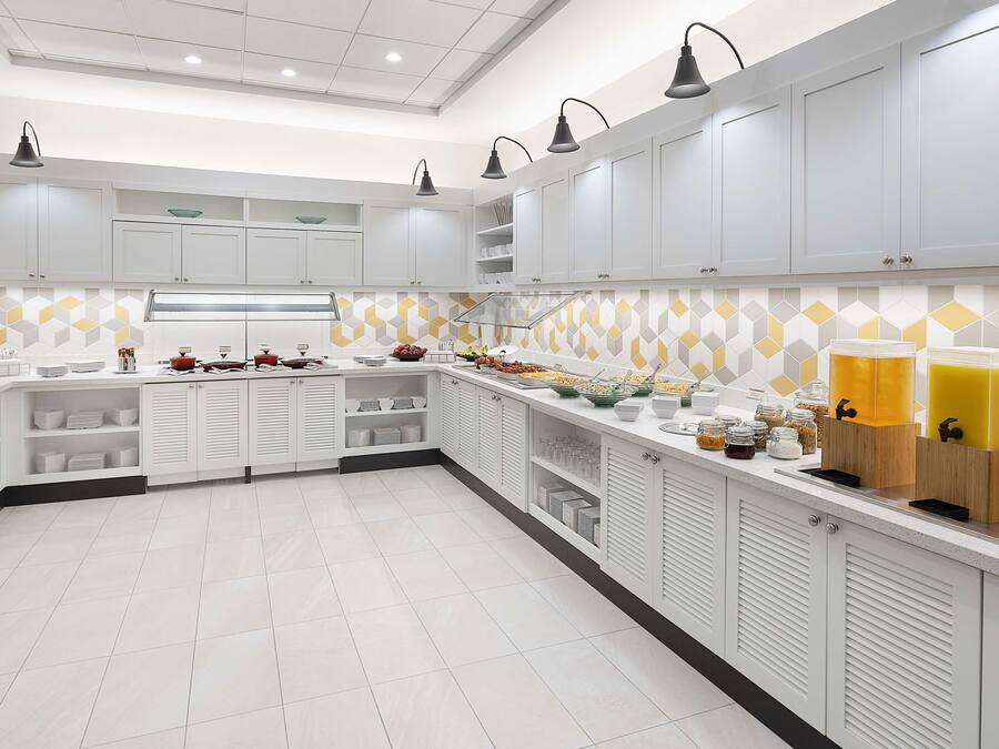 Une cuisine moderne avec des meubles blancs, un îlot central et un bar pour prendre le petit-déjeuner.