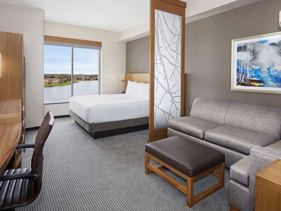 A hotel room with a bed, a sofa, a desk, and a TV.
