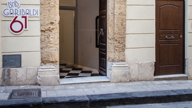 Une entrée d’immeuble avec un arc en pierre, une porte en bois et une enseigne indiquant l’adresse.