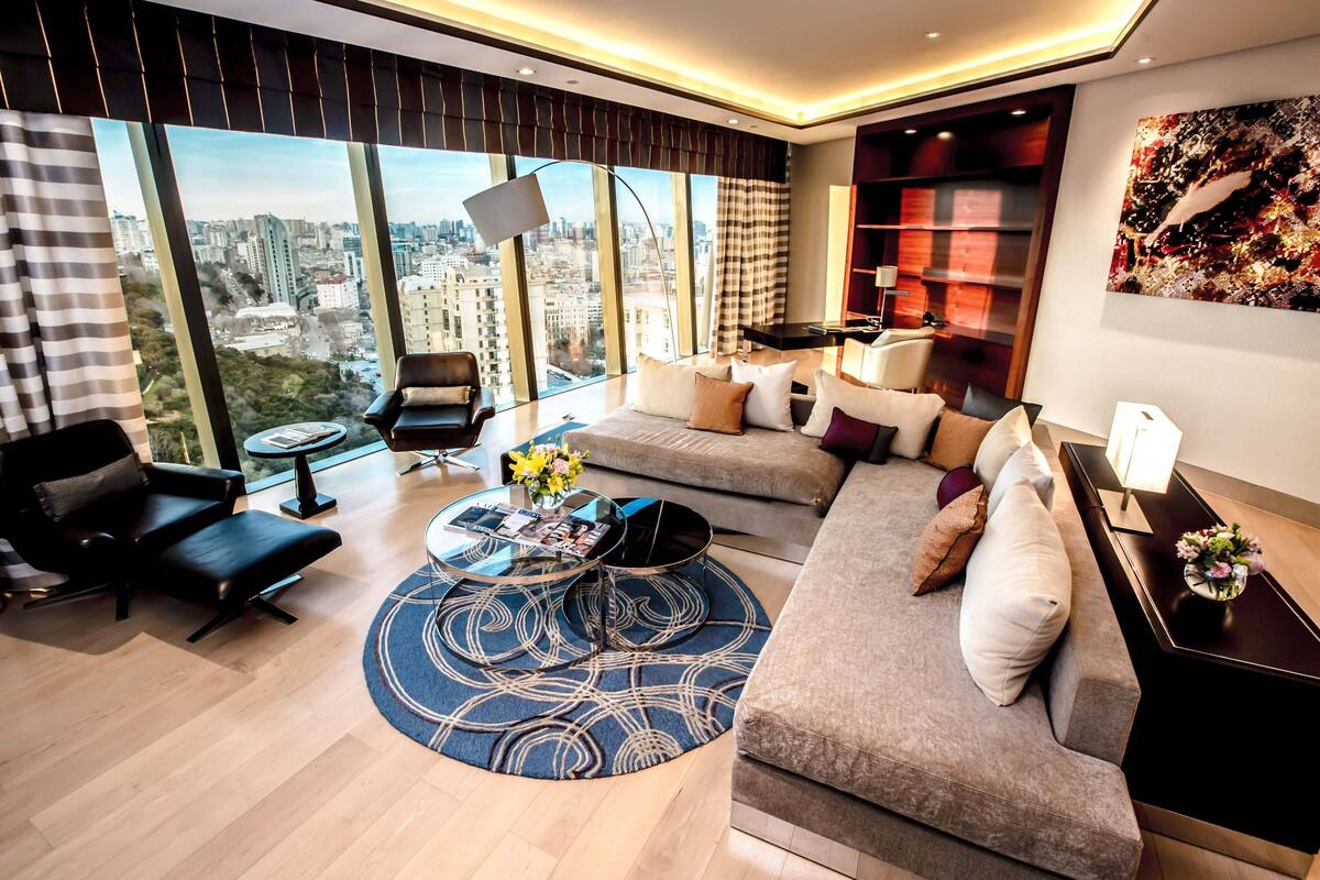 Ein modernes Wohnzimmer mit großem Fenster, einer Couch, einem Couchtisch und einem Bücherregal.