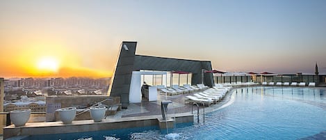 Een binnenzwembad, een buitenzwembad en parasols bij het zwembad