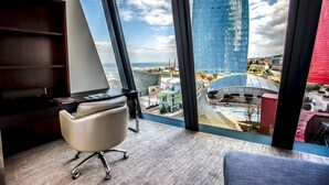 A modern office space with a large window offering a view of a cityscape, including a tall blue building and a Ferris wheel. - Apartments by Fairmont Baku Flame Towers (Baku)