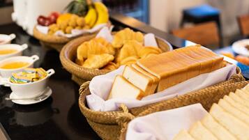 A buffet with various food items including bread, fruits, and pastries.