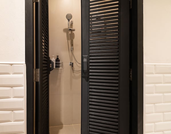 Un baño con ducha, toallero y dispensador de jabón.