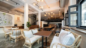 A modern interior with wicker furniture, a map on the wall, and a staircase leading to an upper level.