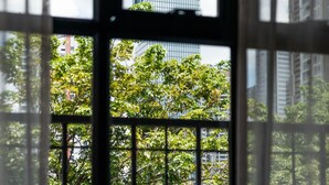 A modern building with a unique architectural design, viewed through a window with vertical blinds.