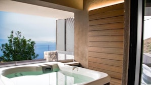 A modern bathroom with a large bathtub, wooden paneling, and a view of the sea. - The View luxury apartments Taormina (Taormina)