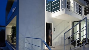 A modern building with a glass entrance, a balcony, and a dining area with chairs. - The View luxury apartments Taormina (Taormina)