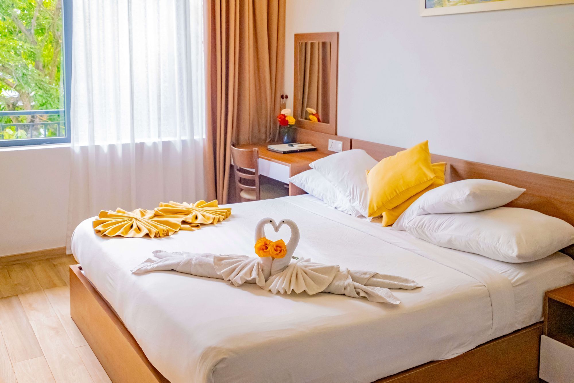 A hotel room with a neatly made bed, a desk, and a chair.