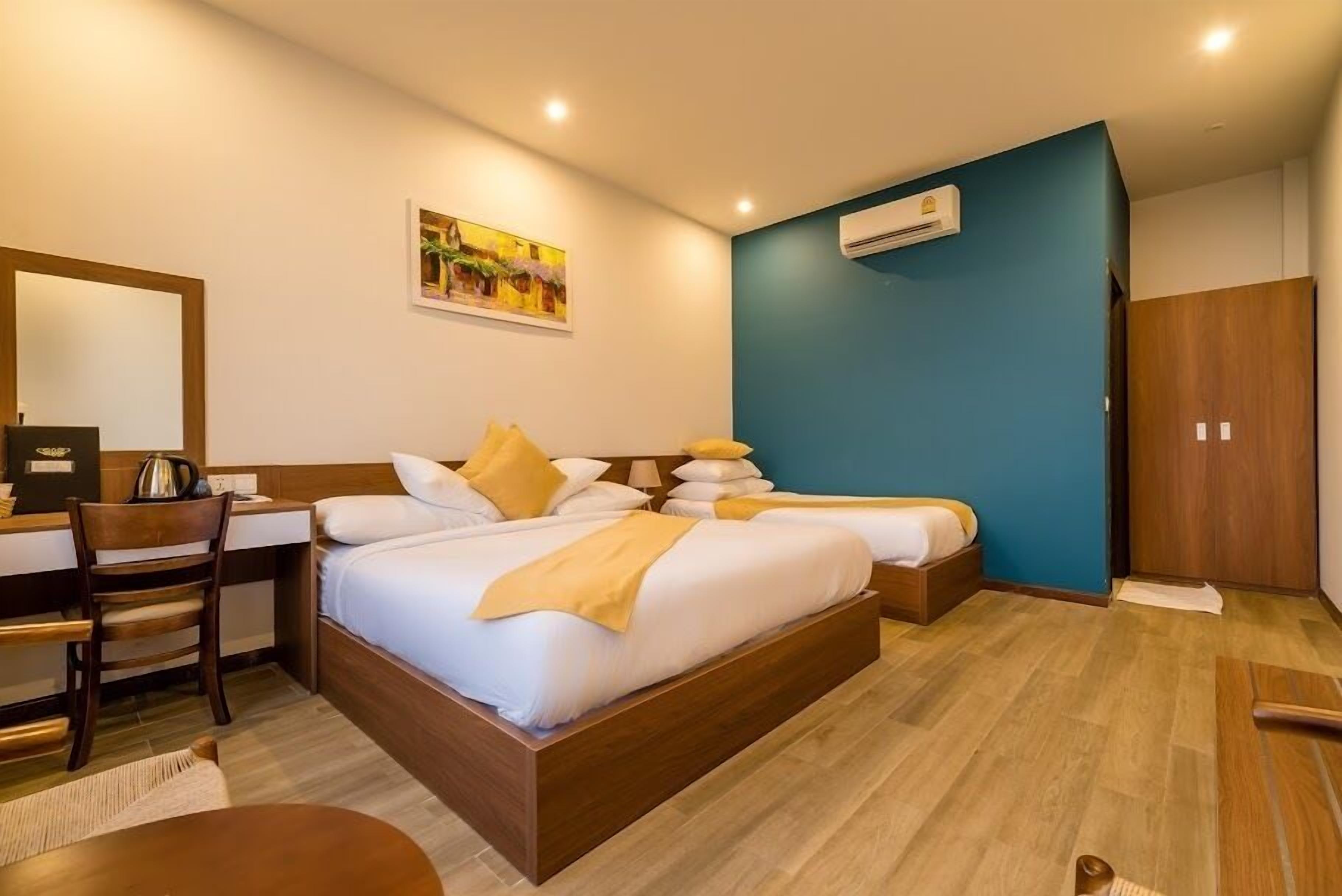 Habitación de hotel con cama, escritorio, silla y un cuadro en la pared.