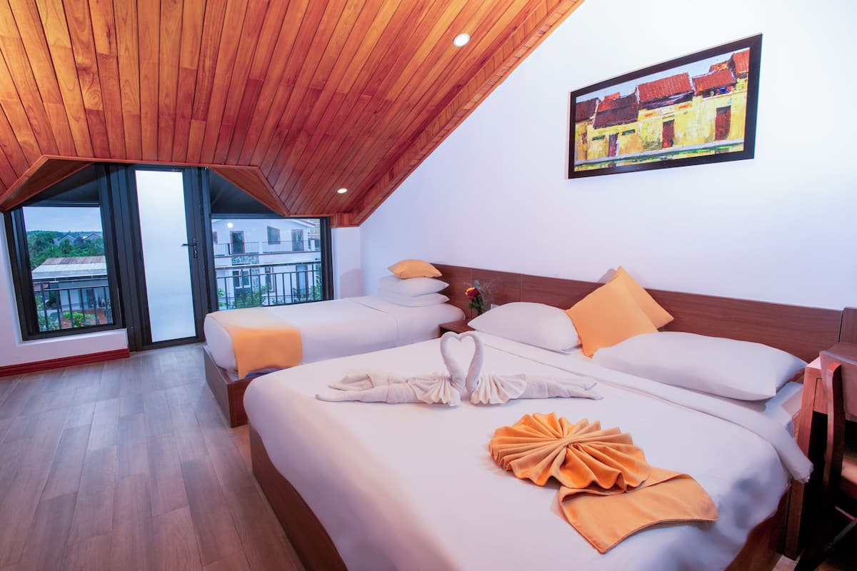 Ein Hotelzimmer mit zwei Betten, Holzboden, großen Fenstern und einem Gemälde an der Wand.