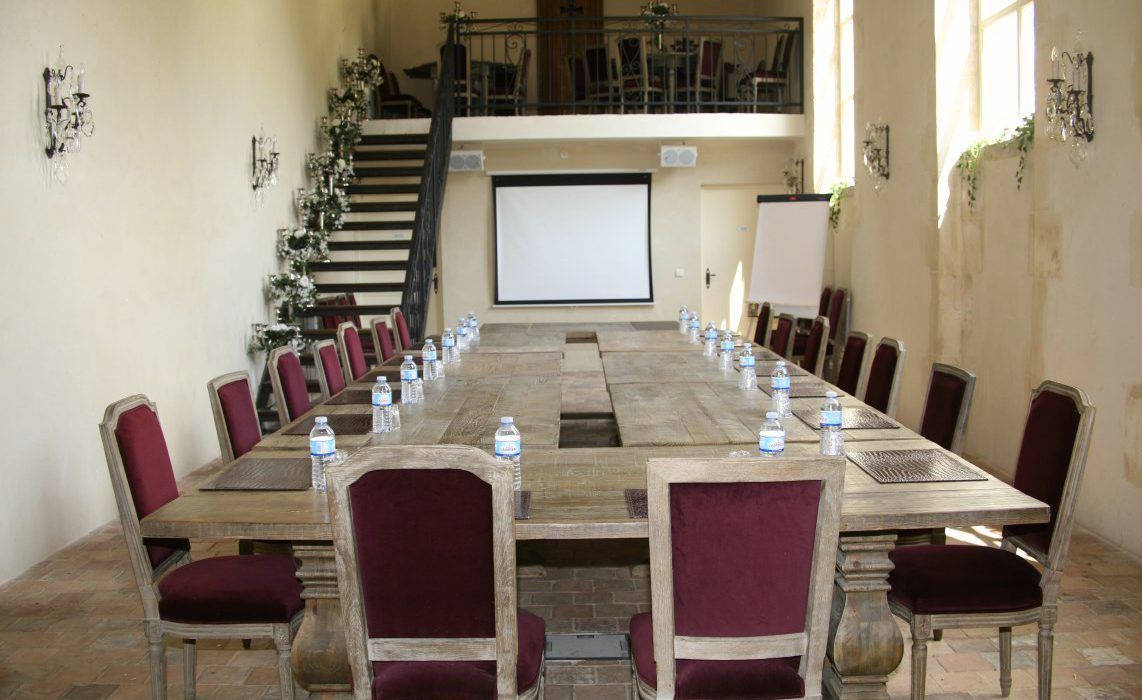 A conference room with a long table, red chairs, and water bottles.