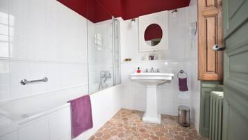 Un baño con cabina de ducha de vidrio, un lavabo blanco y suelo de baldosas.