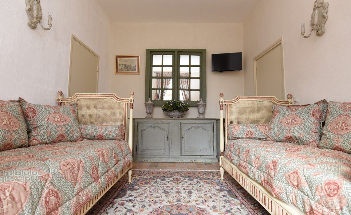 A room with two beds, a television, and a window with curtains.
