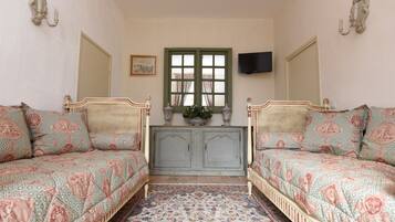 A room with two beds, a television, and a window with curtains.