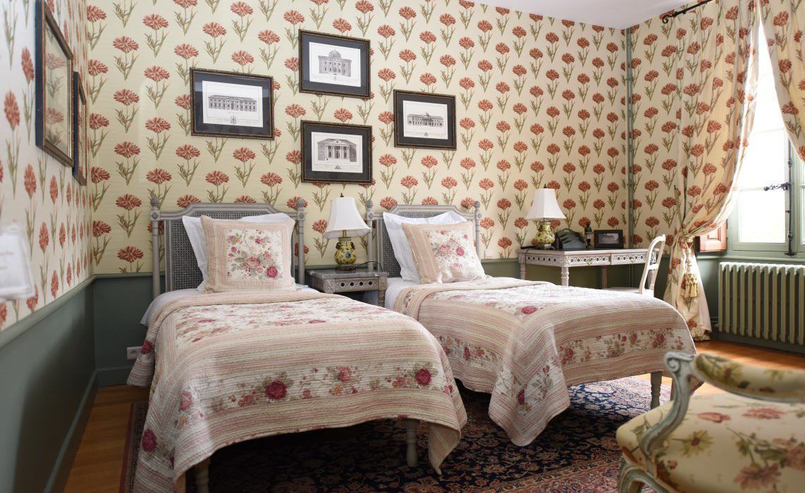 Een kamer met twee bedden, een bureau en een stoel. Er hangen prestaties aan de muur.