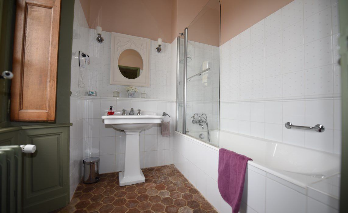 Une salle de bain avec un lavabo sur colonne, un miroir, un espace douche et une baignoire.