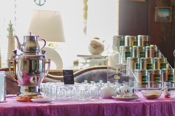 Una mesa con un juego de té, vasos y latas de té.