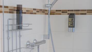 Een douche met een handdouche en een bedieningspaneel aan de muur.