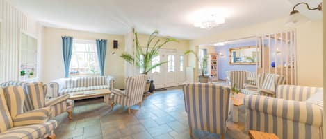 A spacious living room with striped sofas, armchairs, and a wooden coffee table.