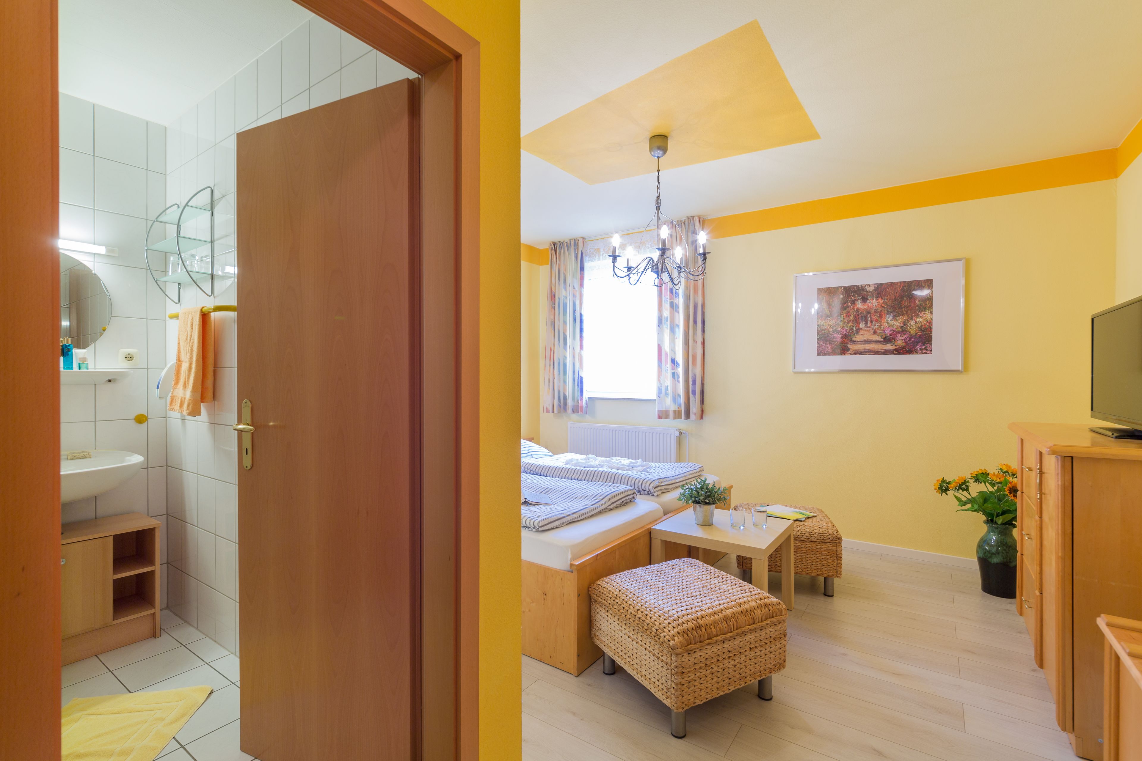 Un dormitorio con cama, mesita de noche y un pequeño rincón de descanso.