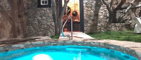 Una piscina con un muro de piedra y una puerta de madera.