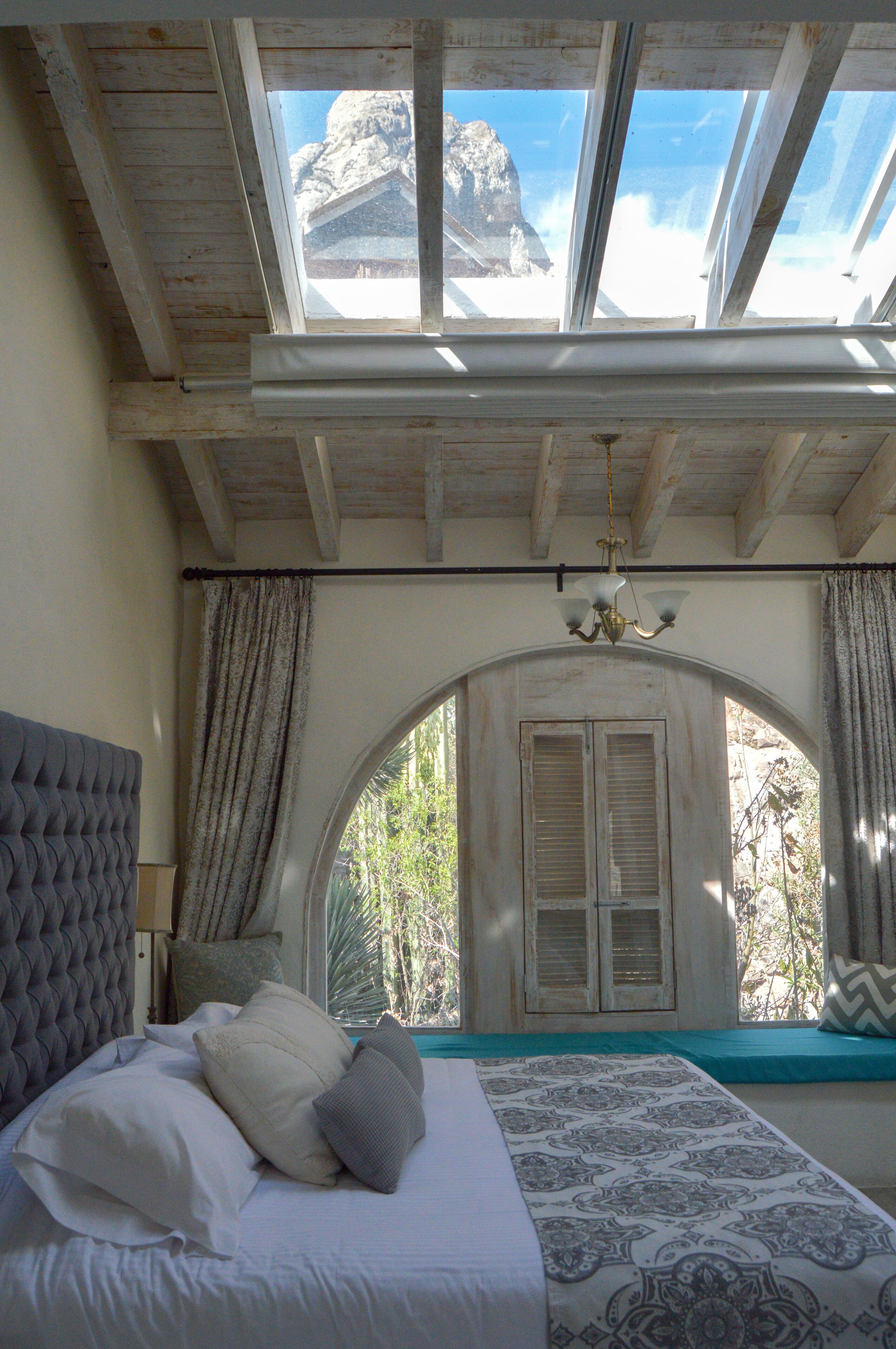 Une chambre avec un grand lit, une fenêtre avec des volets et une vue sur une montagne.