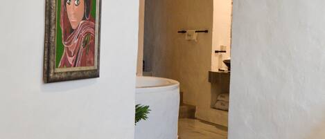 Una escalera con escalones de madera y baldosas estampadas, que conduce a un baño con bañera e inodoro.
