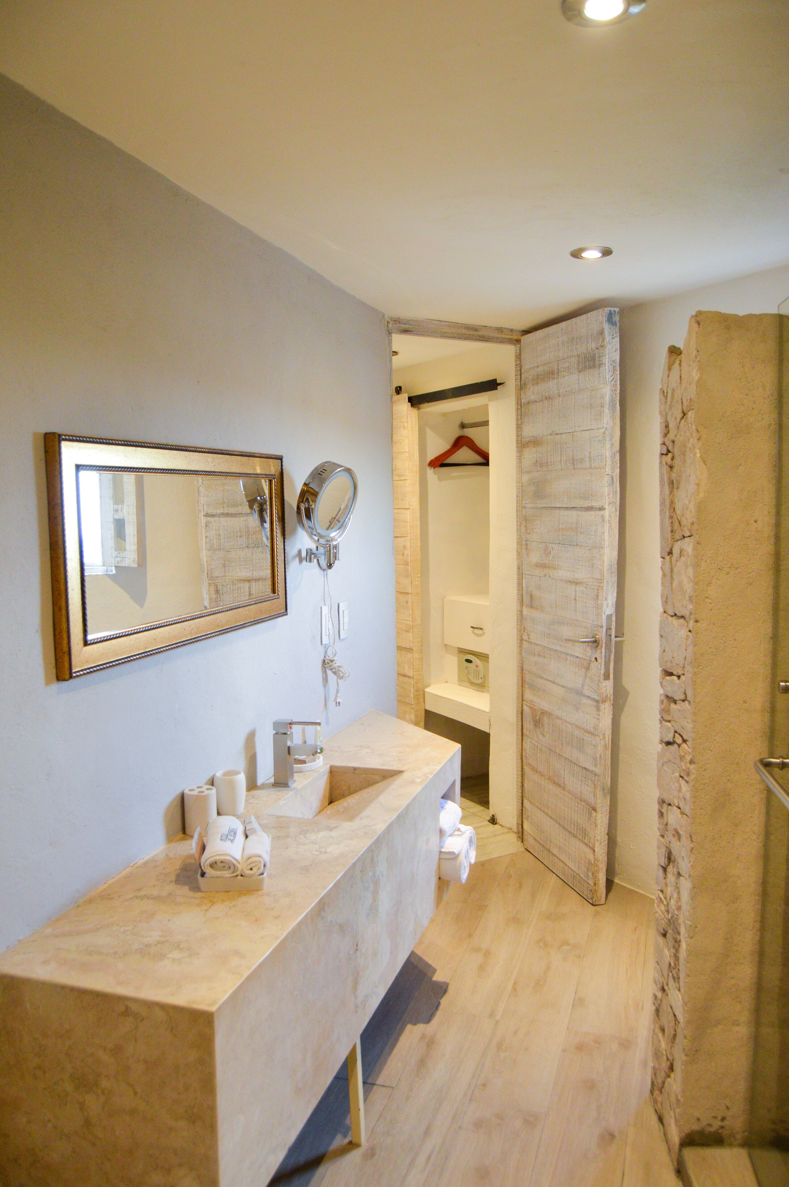 A bathroom with a beige countertop, a mirror, a towel rack, and a shower area.