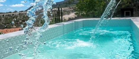 A swimming pool with clear blue water and a waterfall feature.