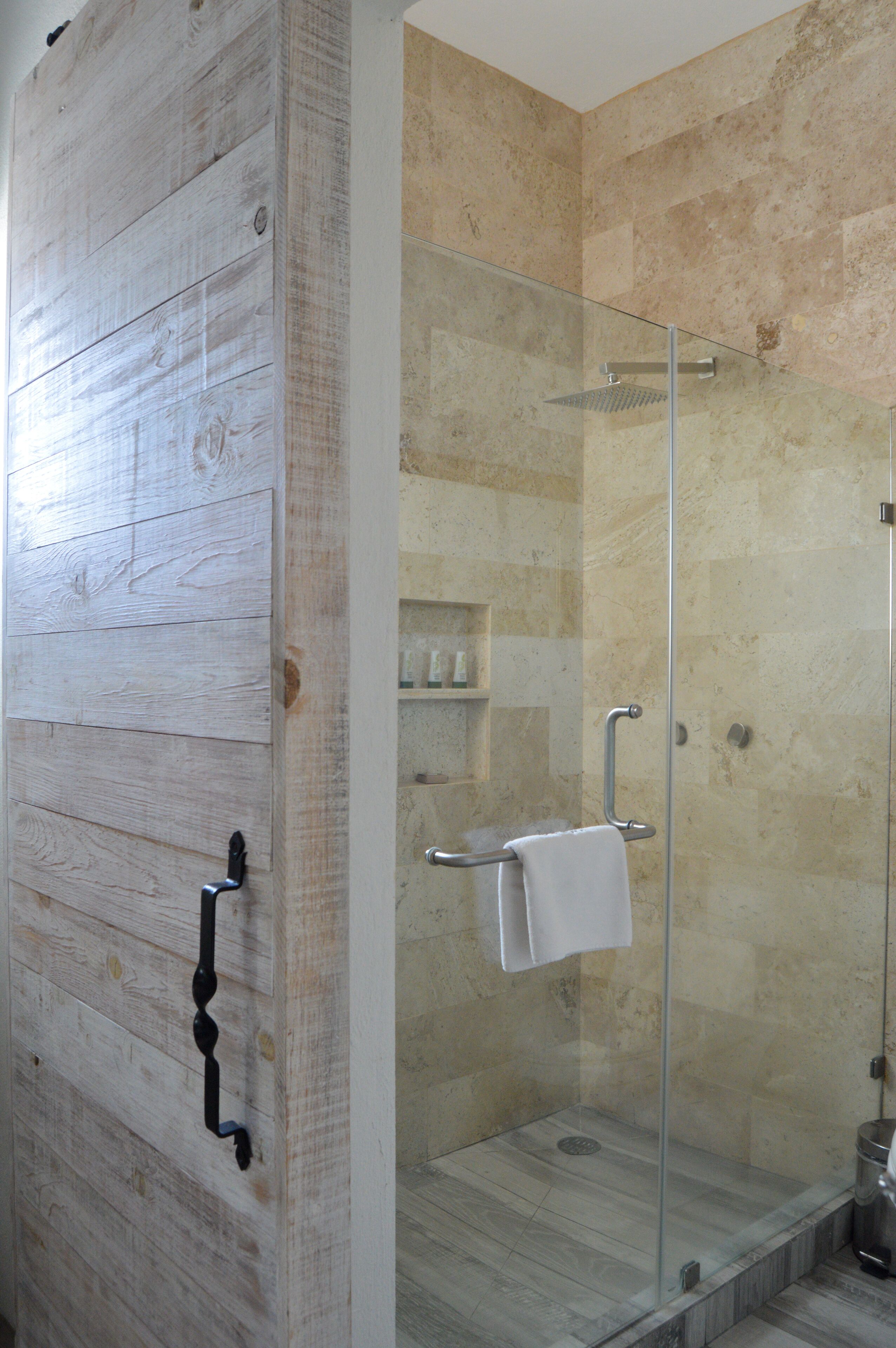 A shower with a glass door, a towel rack, and a marble floor.