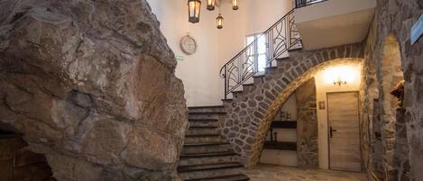 A stone staircase leading to a second floor, a large rock formation, and a wooden chest.