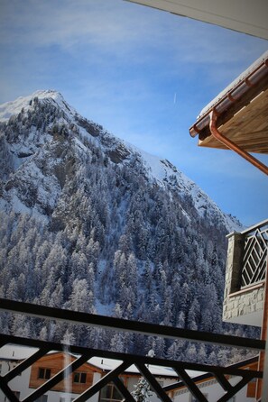 Una montaña con árboles nevados y un edificio de madera con un balcón.