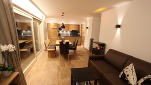 Un salon moderne avec un canapé marron, une table basse et un coin repas comprenant une table et des chaises en bois.