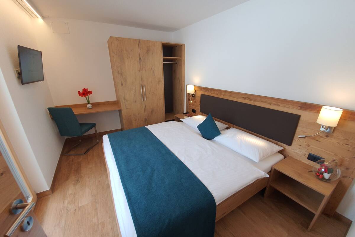 Una habitación de hotel con cama, escritorio y armario.