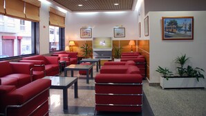 Un hall con asientos rojos, un televisor y obras de arte enmarcadas en las paredes.