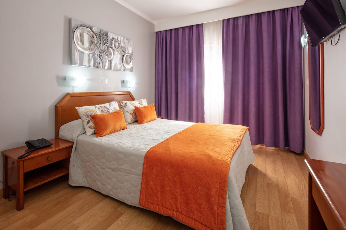 A neatly arranged bedroom with a bed, nightstand, and a wall-mounted artwork.