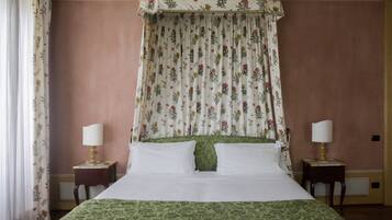 Ein Schlafzimmer mit einem Himmelbett, floralen Vorhängen und zwei Nachttischen mit Lampen.